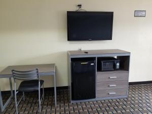 橙县Economy Inn Motel的客房设有书桌和墙上的电视
