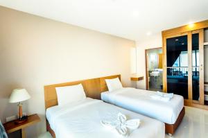 南芭堤雅格居公寓式酒店的一间卧室配有两张床,铺有带弓的白色床单