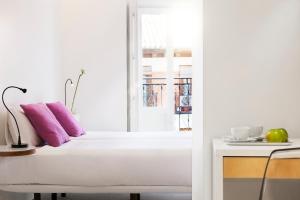 马德里阿奇普酒店的白色的客房配有紫色枕头和窗户