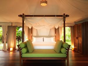 阁遥岛9 Hornbills Tented Camp的一间卧室配有一张带绿沙发的天蓬床