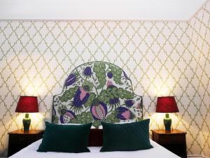 威特尼羊毛酒店的一间卧室配有一张带花卉床头板的床和两盏灯。