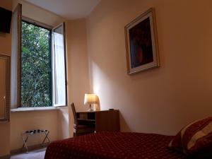 罗马亚提斯酒店的一间卧室配有一张床、一张书桌和一个窗户。