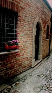 里帕特兰索内Il Vicolo di Ripa B&b的砖砌的建筑,窗户上放着一壶鲜花