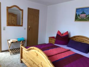 拉德博伊尔Fewo Radebeul Altkötzschenbroda的一间卧室配有一张带紫色枕头的大木床