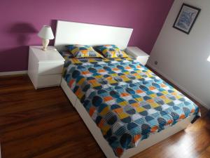 蓬塔德尔加达Varanda do Atlântico的一间卧室配有一张带五颜六色棉被的床