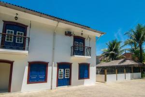 帕拉蒂Pousada Lua Clara的白色的建筑,有蓝色的门和棕榈树