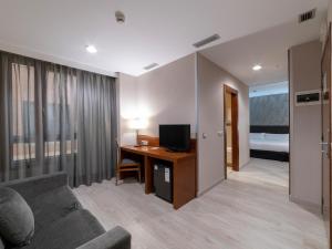 拉斯·罗萨斯·德·马德里拉斯麦塔斯广场酒店的客厅配有沙发和书桌及电视