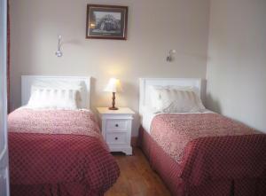 基拉尼红木酒店的一间卧室配有两张床和床头灯。