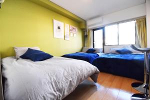 东京LIONS APARTMENT 516的黄色墙壁客房的两张床