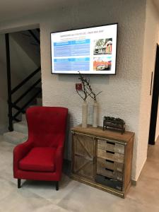 卡拉维塔Filoxenia Hotel & Spa的一张红色椅子,坐在墙上的电视旁边
