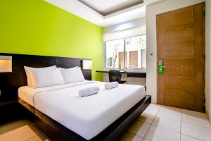 雅加达LeGreen Suite Tondano的卧室配有白色的床和绿色的墙壁