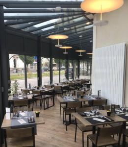 永河畔拉罗什Hôtel de la Gare - Restaurant Bistro Quai的餐厅设有木桌、椅子和窗户。