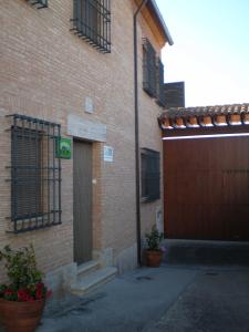 Navas de EstenaCasa Rural María Victoria的砖砌的建筑,有门,有两盆植物