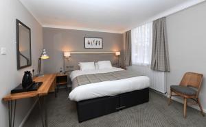 霍伊莱克Green Lodge, Wirral by Marston's Inns的配有一张床和一张书桌的酒店客房