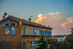 罗马天堂酒店的一座有蓝色百叶窗和云天的建筑