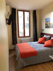 马赛胜利酒店的一间卧室配有一张带红色枕头的床和一扇窗户