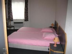 马尔梅迪圣休伯特酒店的一间卧室配有一张带粉色床单的床和一扇窗户。