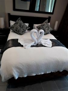 德班Rostalyn Guesthouse的两个天鹅坐在床上