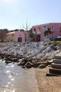 韦利拉特Apartments Zvone1 - at the water front的岩石海岸,有粉红色的建筑背景