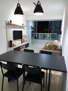 瓜拉派瑞NOVO EDIFICIO VIENA - ATRAS do PRAIA CENTER的客厅配有黑色餐桌和椅子