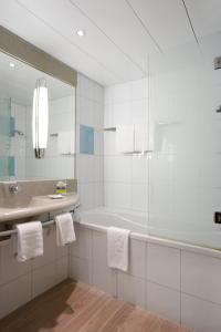 格拉特布鲁格诺富特苏黎世机场会展中心酒店的带浴缸、水槽和镜子的浴室