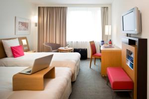 格拉特布鲁格诺富特苏黎世机场会展中心酒店的酒店客房设有两张床和一张桌子上的笔记本电脑