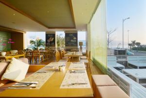 岘港Fusion Suites Da Nang - Daily Reflexology Inclusive的餐厅设有桌椅和大窗户。