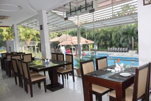 海得拉巴Mrugavani Resort & Spa的一间带桌椅的用餐室和一个游泳池