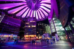 柏林Suite im Sony Center am Potsdamer Platz的城市中一座大建筑,晚上有紫色的灯光