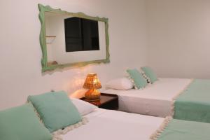 图卢姆波萨达蓬彼德拉海滩酒店的一间卧室配有两张床、镜子和灯