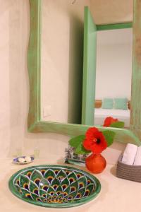 图卢姆波萨达蓬彼德拉海滩酒店的浴室水槽设有绿色镜子和红色花卉