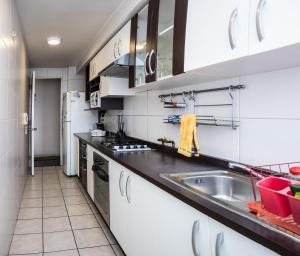 圣地亚哥森特诺公寓酒店的厨房配有白色橱柜和水槽