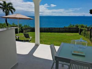 哥西尔Studio Cozy Mélissa Élégance - GUADELOUPE , LE GOSIER , DAMPIERRE - AVEC PLEINE VUE MER - OCÉAN à 180 degrés的一张桌子和椅子,享有海景