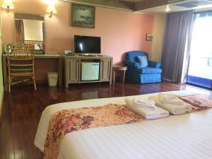 南邦宾大酒店的一间卧室配有一张床、一台电视和椅子