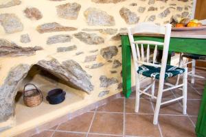 MirsíniAgrilos Οlive Τree Αpartment的一间设有石墙、桌子和椅子的房间