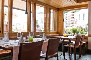圣莫里茨Hauser Hotel St. Moritz的用餐室设有桌椅和窗户。
