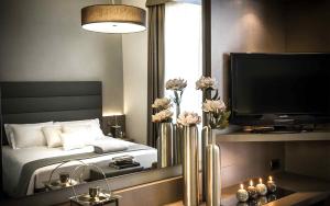 基瓦索Hotel Chivasso的一间卧室配有一张床、一台电视和鲜花