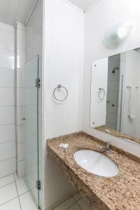 阿雷格里港Hotel Expressinho Aeroporto的一间带水槽和玻璃淋浴的浴室