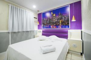 南圣卡埃塔诺Calamares Hotel São Caetano的一间设有白色床和紫色墙壁的客房