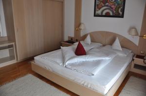 梅拉诺布伦纳酒店的一张白色的床,上面有红色枕头