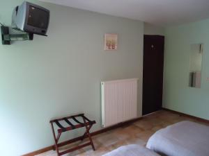 Bras-Haut拉科迈耶酒店的卧室配有一张床,墙上配有电视。