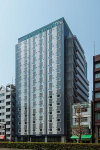 东京东京浅草桥鲁特因大酒店的一座高大的灰色建筑,位于一些建筑前面
