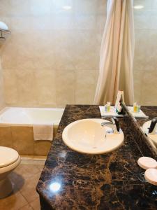 多哈库拉公园多哈酒店的浴室配有盥洗盆、卫生间和浴缸。
