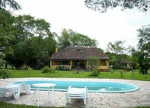 巴热查卡勒达斯洛塞拉斯农家乐的一个带椅子和桌子的游泳池以及一座房子