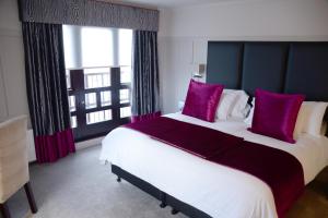伦弗鲁Glynhill Hotel & Spa near Glasgow Airport的一间卧室配有一张带紫色枕头的大床