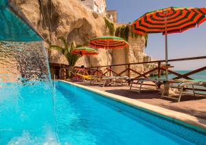 维耶斯泰Hotel Seggio的一个带遮阳伞和椅子的游泳池以及大海