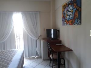 瓜拉派瑞Fragata Hotel的一间卧室配有一张桌子、一台电视和一个窗口