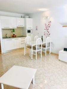 科斯塔特吉塞New Canela Apartment的厨房配有白色橱柜和桌椅