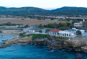 Ayia TriasTheresa Hotel at Karpaz Peninsula的水面上岩石岛房屋的空中景观