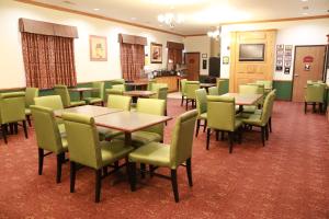 West Point地平线套房汽车旅馆的用餐室配有桌子和绿色椅子